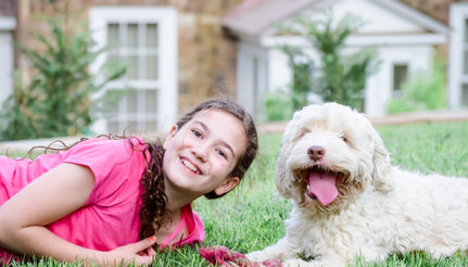 Little girl and a cream Australian Labradoodle smiling at the camera